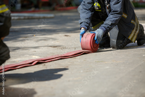 Fireman unwinding red fire hose outdoors