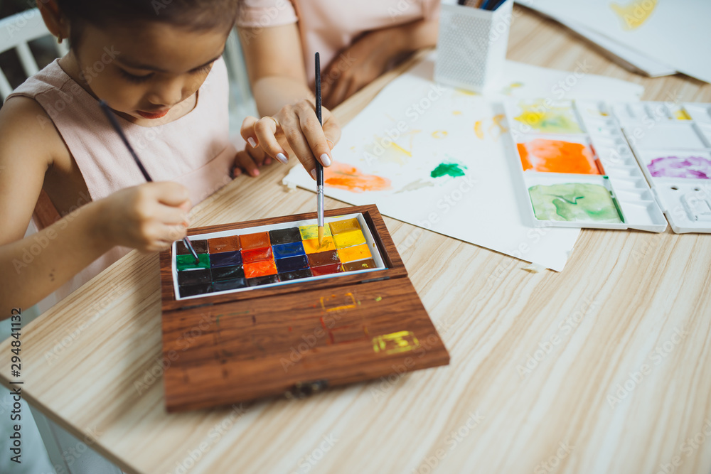 Young Asian beautiful mom with her daughter kid painting at home. Young Asian beautiful mom with her daughter kid painting at home.