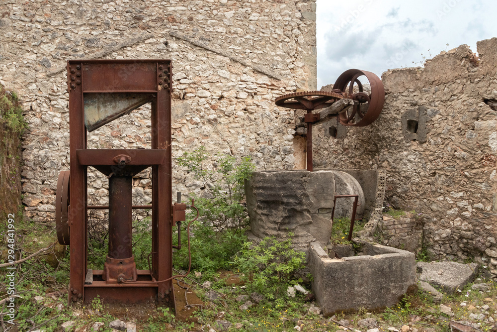 rustd olive presses in ruined olive oil factory in abandoned village Palia Plagia, Greece