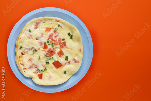 omelet on a blue plate on an orange background. healthy breakfast top view.