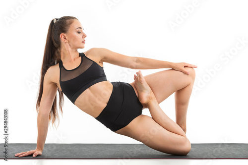 A beautiful young woman gymnast with dark long hair does warm-up and stretch her muscles.