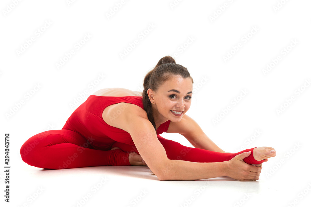 A beautiful young female gymnast with dark long hair stuffed in a horse tail in a red sports elastic suit does warm-up and stretch muscles. A beautiful young female gymnast with dark long hair stuffed in a horse tail in a red sports elastic suit does warm-up and stretch muscles.