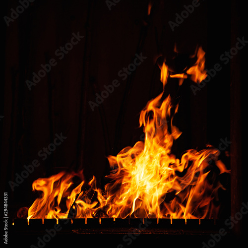 Fire flame on a dark background. Burning fire at night. Bright bonfire in the barbecue, fireplace and hearth.