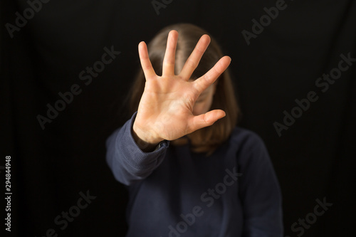 A crying woman covers her face with her hand on a black background. The concept of domestic violence.