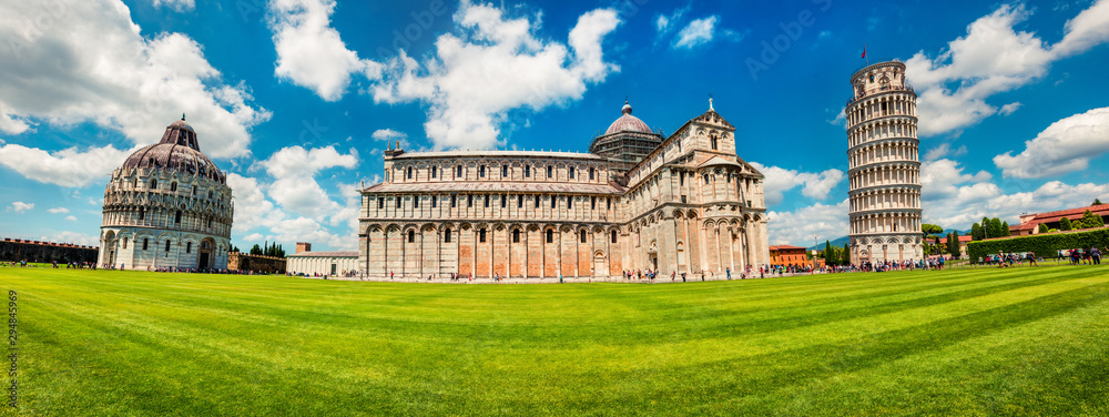 Panoramic spring view of famous Leaning Tower in Pisa. Sunny morning scene with hundreds of tourists in Piazza dei Miracoli (Square of Miracles), Italy, Europe. Traveling concept background.