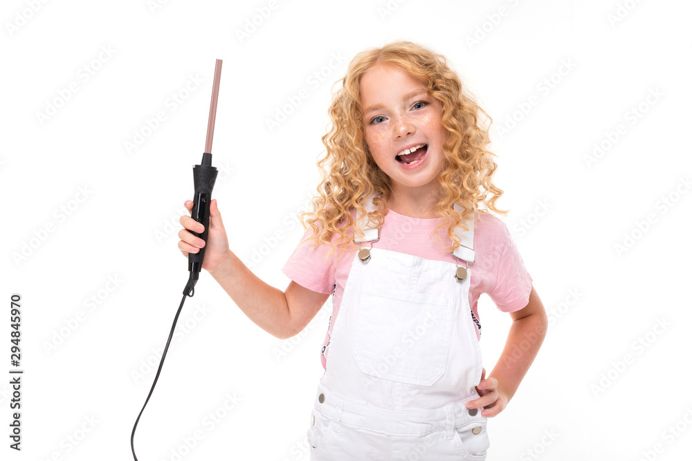 A little girl with red heap hair in a jersey, white jumpsuit, white sneakers spins her hair on a thin plow. A little girl with red heap hair in a jersey, white jumpsuit, white sneakers spins her hair on a thin plow.