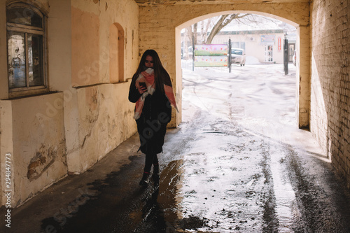 Young woman using smart phone while walking through archway in city during winter © finwal89