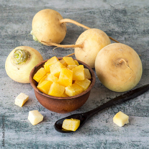 Yellow turnip, boiled and fresh uncooked on an old table. Selective focus.