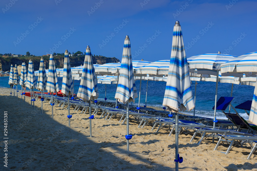 Morning sea beach with deck chairs and umbrellas in sand Morning sea beach with deck chairs and umbrellas in sand