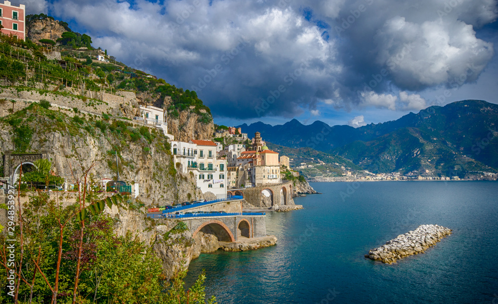 The seaside village of Atrani with mountains in the distance surrounded by turquoise blue water. One of the fairy villages, part of the Amalfi Coast (Costiera Amalfitana)