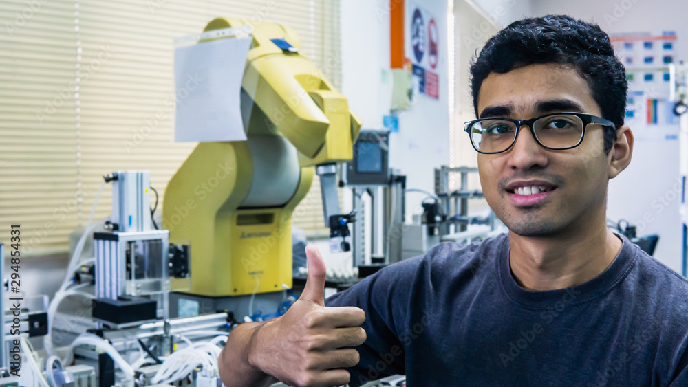 A young Malay engineering student with spectacles working in the lab and show a thumbs up sign. A young Malay engineering student with spectacles working in the lab and show a thumbs up sign.