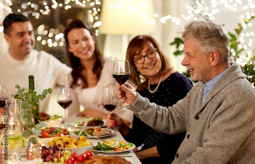 celebration  holidays and people concept - happy grandfather with glass of red wine toasting with family having dinner party at home