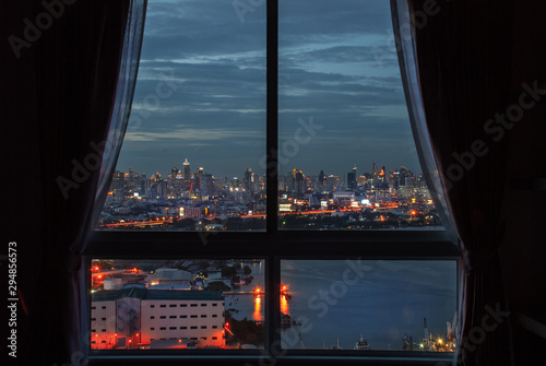 The beautiful view of Bangkok, the beautiful skyscrapers along the Chao Phraya River during sunset seen through a bedroom window.