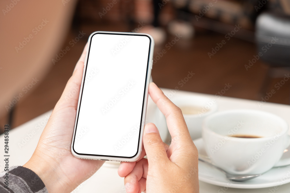Women holding mobile phone with blank screen in coffee cafe