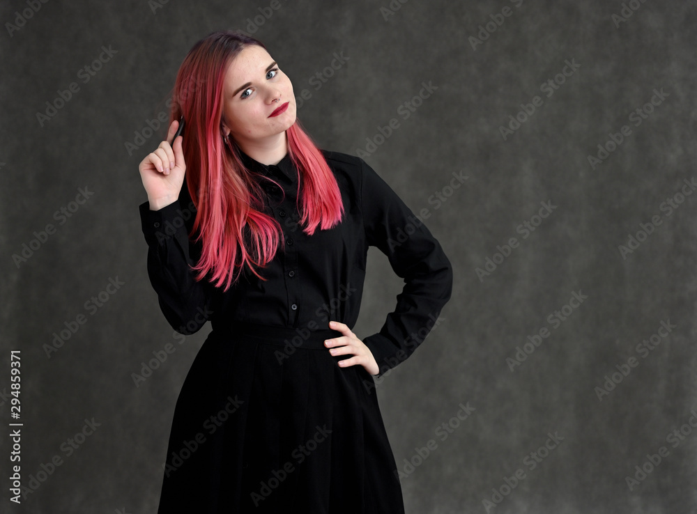 Portrait of a pretty student girl with colored hair in a black suit on a gray background in the studio.
