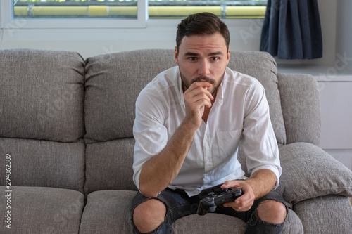 Portrait young handsome man playing video game to win, Holdong joystick on sofa at home