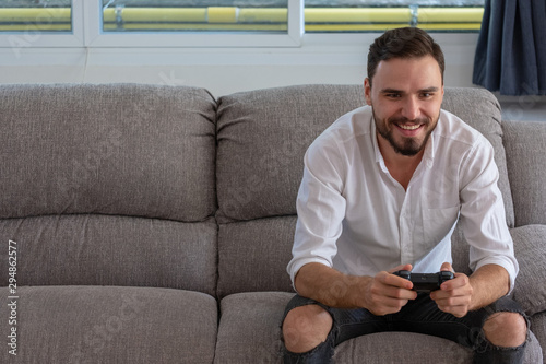 Portrait young handsome man playing video game to win, Holdong joystick on sofa at home