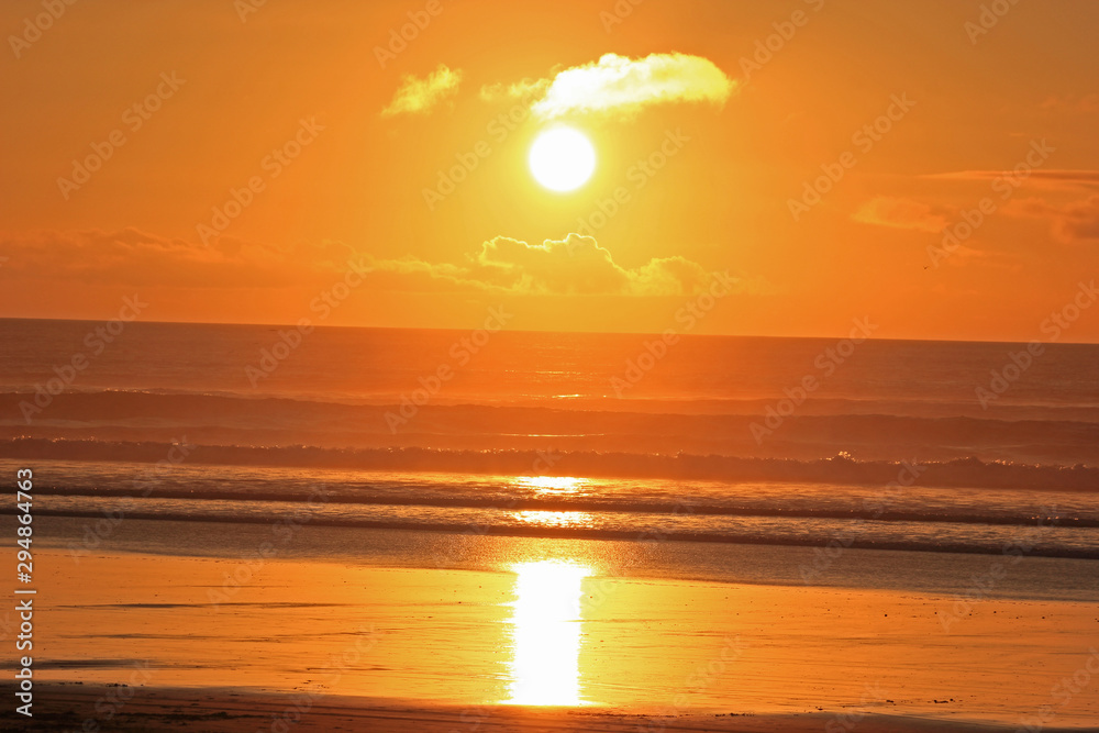 orange and yellow sunset at muriwai beach
