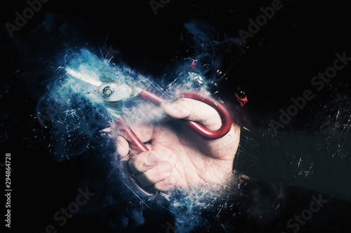 man hand holding big scissors on black background  - concept of cutting waste or human resources - optimization photo
