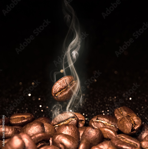 Roasted coffee beans. Seeds of freshly roasted coffee with smoke. Coffee beans closeup with emphasis on the grain with smoke.