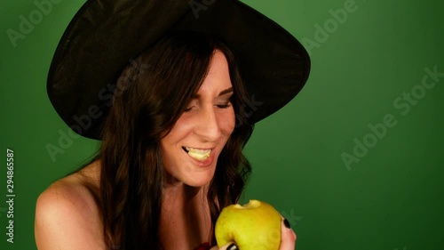 Closeup brunette woman eagerly eating green apple.green background.