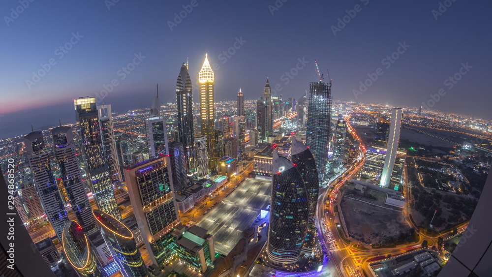 Obraz premium Skyline of the buildings of Sheikh Zayed Road and DIFC aerial day to night timelapse in Dubai, UAE.