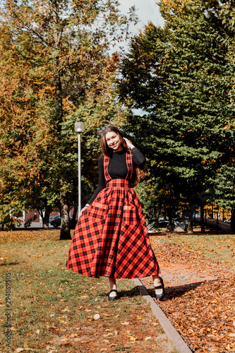 Girl with long brown hair in autumn park. Girl with Scottish long red dress.