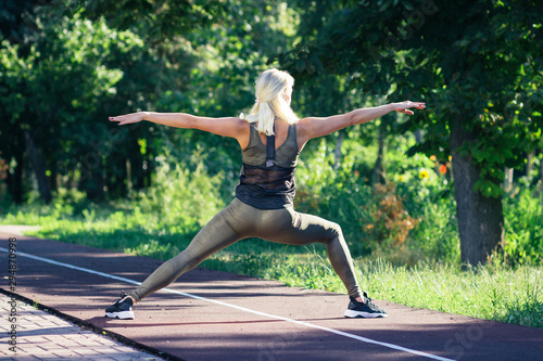 Beautiful young woman makes sport exercises on the sport ground, blurred background