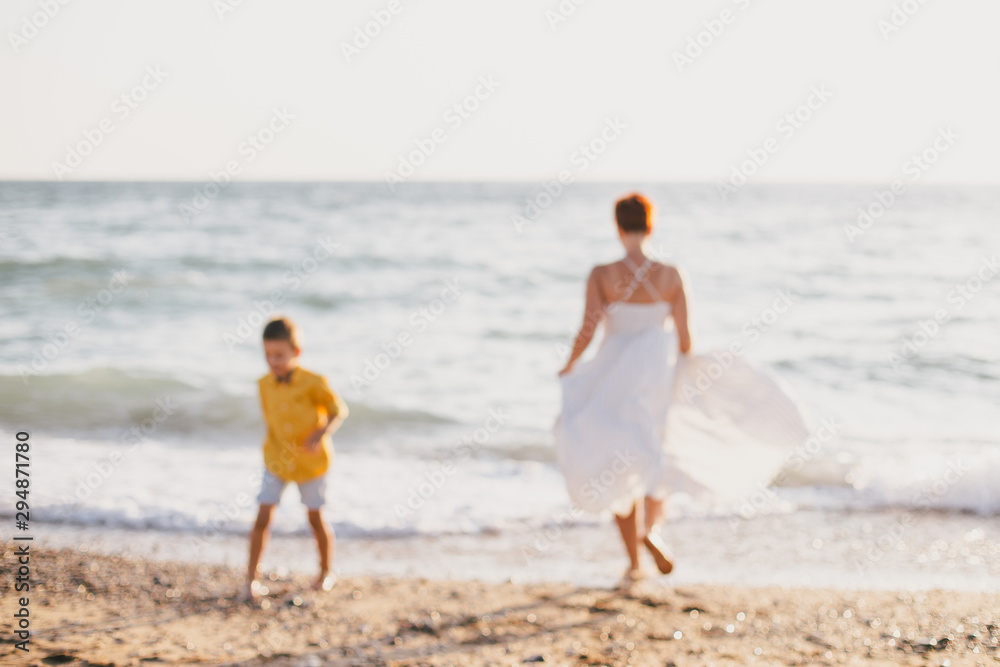 Young mother and son having fun on beach at sunset