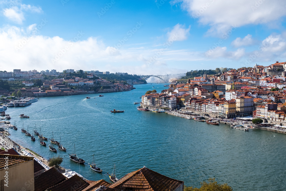 View of the Douro River snaking through the city of Porto from the Ponte Luiz bridge with traditional boats tied up on the river