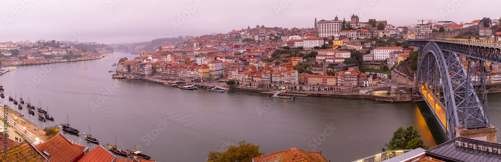Obraz premium Panoramic view of the Douro River snaking through the city of Porto with the Ponte Luiz bridge in the foreground with traditional boats tied up on the river taken at dawn