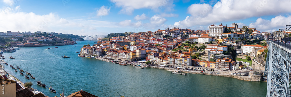 Panoramic view of the Douro River snaking through the city of Porto from the Ponte Luiz bridge with traditional boats tied up on the river
