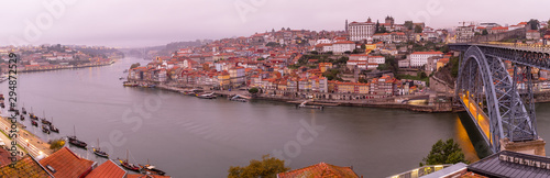 Panoramic view of the Douro River snaking through the city of Porto with the Ponte Luiz bridge in the foreground with traditional boats tied up on the river taken at dawn