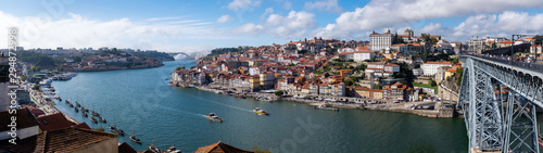 Panoramic view of the Douro River, snaking through the city of Porto with the Ponte Luiz bridge in the foreground and traditional boats tied up on the river. © Wise Dog Studios