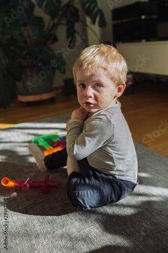 Kleinkind sitzt auf dem Boden und schaut in die Kamera photo