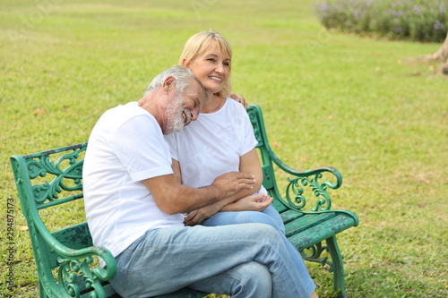 side view of elderly caucasian couple sitting and embracing in park in summer time © feeling lucky