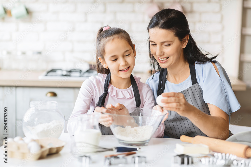 Little girl and her beautiful mother having fun cooking together Little girl and her beautiful mother having fun cooking together