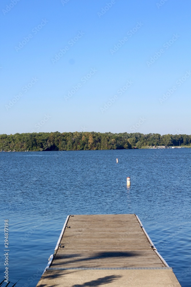 The wood dock at the lake in the country on sunny day.