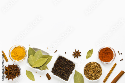 set of assorted colorful spices in white bowls on a white background, flat lay, top view, with copy spice