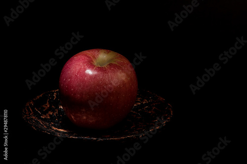 red apple on a gold plate black background
