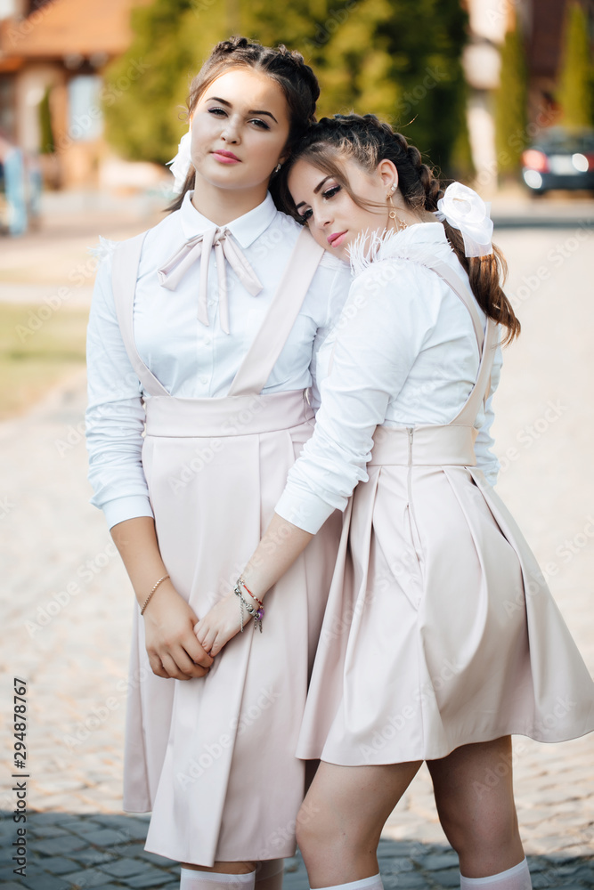Naklejka premium Happy teenage girls having fun. People, fashion and summer concept - happy smiling pretty teenage girls in school uniform. School girl posing. Back to school