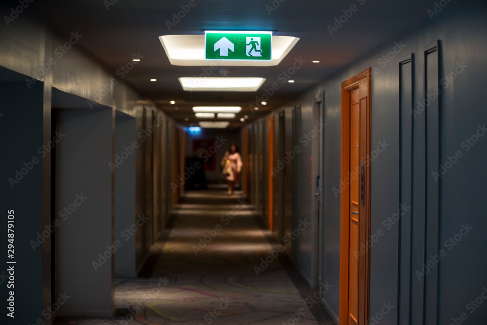 Sign : Emergency exit sign at path way indoor building public facility that emergency escape route is left. (fire, building, health or safety) require exit signs to be permanently lit Sign : Emergency exit sign at path way indoor building public facility that emergency escape route is left. (fire, building, health or safety) require exit signs to be permanently lit