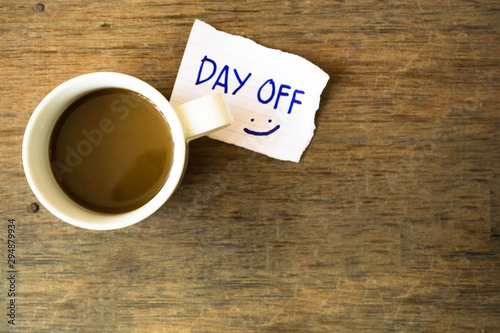 Cup of hot coffee with message DAY OFF on dark wood background..