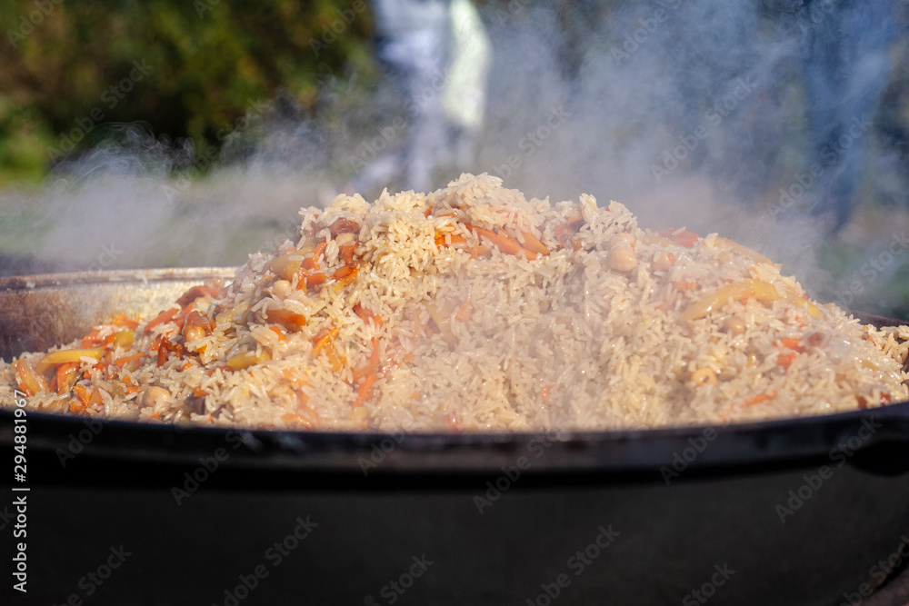 Rice in a cauldron. Cooking rice with meat on an open fire. Delicious food prepared in the fresh air. Rice stewed with vegetables. Shooting in natural light. Rice in a cauldron. Cooking rice with meat on an open fire. Delicious food prepared in the fresh air. Rice stewed with vegetables. Shooting in natural light.