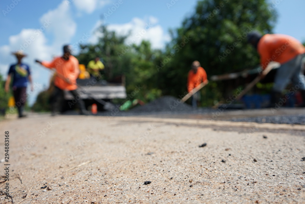Repairing a damaged road By adjusting the level with asphalt mixed with small stones (picture blurred)