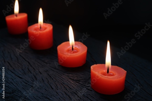 Burning red candles on black wooden background