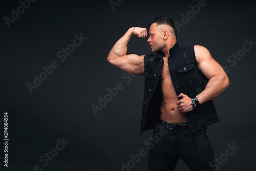 Strong and handsome young man with muscles and biceps. Studio shooting on black background.