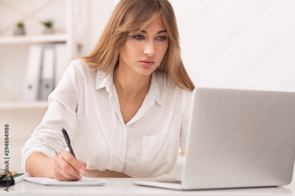 Fototapeta premium Office Girl Sitting At Laptop Taking Notes At Workplace