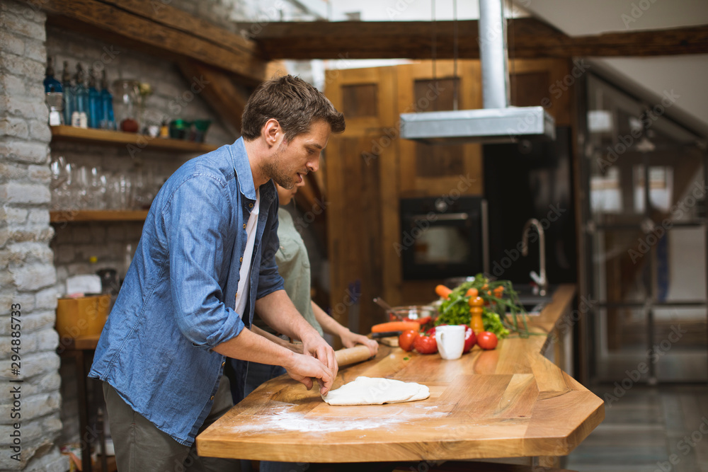 Young couple making pizza in rustic kitchen together