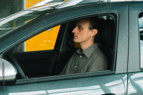 A man in a smart casual wear sits in a car © voffka23